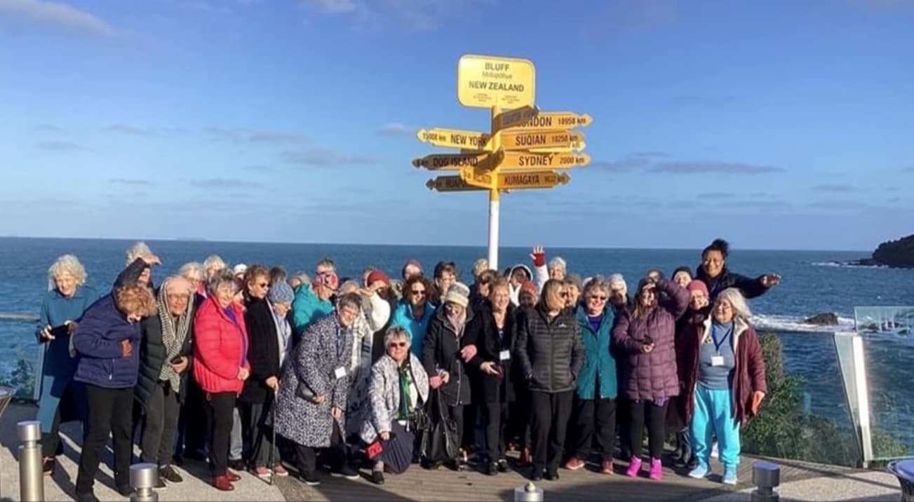 A large gathering of members at the Bluff signpost on the Southland coast
