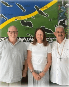 Lorraine Macmillan with her husband Paul and Bishop Cardone in front of a painted map of the Solomon Islands